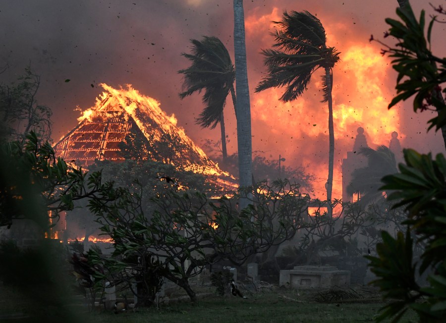 FILE - The hall of historic Waiola Church in Lahaina and nearby Lahaina Hongwanji Mission are engulfed in flames along Wainee Street on Aug. 8, 2023, in Lahaina, Hawaii. Soon after Lahaina Hongwanji Mission burned in a wildfire that decimated much of the historic coastal town, the Japanese Buddhist temple's resident minister was desperate to go back and see what remained. Now, he's more hesitant. The Rev. Ai Hironaka and other Lahaina residents are grappling with a range of feelings as Maui authorities plan to begin allowing them back into what has become known as the "burn zone." (Matthew Thayer/The Maui News via AP, File)