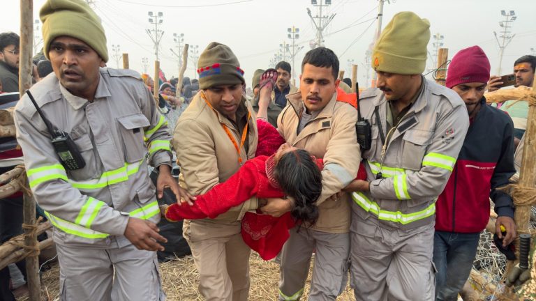 india-maha-kumbh-festival-stampede-officers-carry-woman.jpg